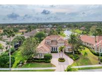 Expansive home features a tiled roof, manicured landscaping, and a circular driveway with palm tree centerpiece at 6822 Dominion Ln, Lakewood Ranch, FL 34202