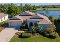 Beautiful lakefront property featuring lush landscaping and a screened lanai at 711 Planters Manor Way, Bradenton, FL 34212