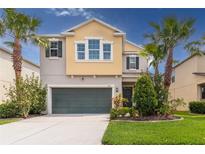 Charming two-story home featuring a two-car garage and well-manicured landscaping with palm trees at 1570 Ludington Ave, Wesley Chapel, FL 33543
