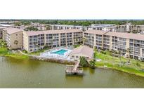 Scenic aerial view of lakeside condos featuring a pool, clubhouse, and private dock for outdoor enjoyment at 3821 Lake Bayshore Dr # H-507, Bradenton, FL 34205