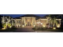 Exterior night shot of home featuring stone facade and manicured landscaping with accent lighting at 5313 Greenbrook Dr, Sarasota, FL 34238