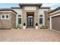 Close-up view of home showcasing stone accents, a tile roof, brick driveway, and manicured landscaping that create curb appeal at 5313 Greenbrook Dr, Sarasota, FL 34238