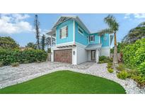 Charming light blue two-story home with a paver driveway, lush landscaping, and a garage at 5930 Briarwood Ave, Sarasota, FL 34231