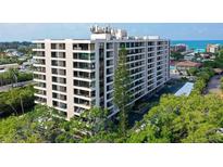 Exterior of the modern condo building showing multiple floors, balconies, and nearby greenery at 6415 Midnight Pass Rd # 607, Sarasota, FL 34242