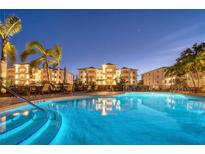 Beautifully lit outdoor pool with lounge chairs, palm trees, and condo buildings at night at 9203 Griggs Rd # B102, Englewood, FL 34224
