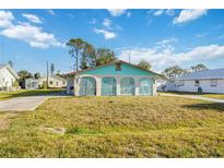 View of the home's arched entry showing the front exterior with large yard and driveway at 270 E Langsner St, Englewood, FL 34223