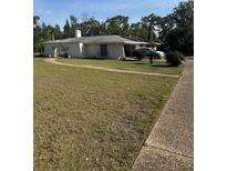 Wide view of home with white exterior, mature trees, and long driveway on expansive lawn at 3052 51St St, Sarasota, FL 34234