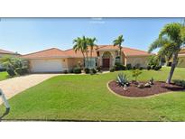 Charming single-story home with a well-manicured lawn and vibrant landscaping, including palm trees and a decorative rock garden at 417 Firethorn Ave, Englewood, FL 34223
