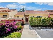 Charming single-story home with a red tile roof, vibrant flowers, and a welcoming entrance gate at 5366 Huntingwood Ct # 14, Sarasota, FL 34235