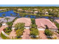 Beautiful aerial view of homes with red brick roofs surrounded by lush greenery and a serene lake at 5816 Helicon Pl, Sarasota, FL 34238