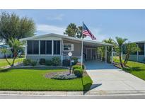 Charming home featuring a screened-in porch, covered parking, and an American flag waving proudly at 8402 Princess Ct, Palmetto, FL 34221