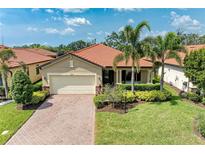 Charming single-story home with a red tile roof, brick driveway, and well-manicured landscaping at 10015 Marbella Dr, Bradenton, FL 34211