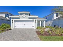 Charming exterior showcasing a two-car garage, stone driveway, and nicely landscaped front yard of this new home at 10054 Cross River Trl, Parrish, FL 34219