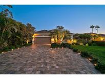 Charming home featuring a paved driveway, manicured landscaping, and exterior lighting at 13 Bayhead Ln, Osprey, FL 34229