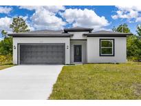 Modern home with a gray garage door, well-maintained lawn, and classic black trimmed entry at 158 Chickering St, Port Charlotte, FL 33954