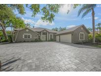 Charming single-story home with a large driveway and a two-car garage surrounded by lush landscaping at 1693 Landings Ln, Sarasota, FL 34231