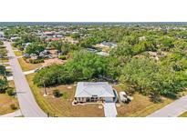 Captivating aerial view of home featuring mature landscaping and a metal roof at 18399 Burkholder Cir, Port Charlotte, FL 33948