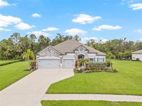 Beautiful single-story home with stone accents, a three-car garage, and lush landscaping at 2707 162Nd E Ave, Parrish, FL 34219