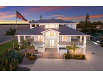 Stunning waterfront home featuring multiple balconies, a metal roof, and ample parking, all set against a colorful sunset at 327 Riverpoint Ne Dr, Bradenton, FL 34208
