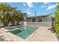 Beautiful in-ground pool and jacuzzi are surrounded by palm trees and patio with lounge chairs at 424 62Nd St, Holmes Beach, FL 34217