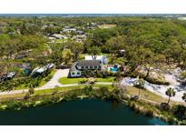 Stunning aerial view of a two-story home next to a peaceful lake, surrounded by lush greenery and tall trees at 5307 22Nd W Ave, Bradenton, FL 34209