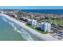 Gorgeous aerial view of beachfront condos with a beautiful white sand beach, turquoise ocean water, and lush green landscaping at 1000 Longboat Club Rd # 604, Longboat Key, FL 34228