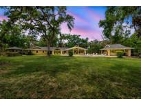 Expansive backyard featuring a manicured lawn, mature trees, and relaxing pool with poolside cabana and covered lounge area at 1240 Fox Creek Dr, Sarasota, FL 34240