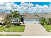 Charming single-Gathering home with well-manicured lawn, mature palm trees, and a three-car garage at 15612 Trinity Fall Way, Bradenton, FL 34212
