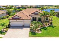 Beautiful waterfront home featuring a lush green lawn and meticulous landscaping at 20114 Uffizi Ct, Venice, FL 34293