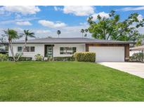 Charming home with a well-manicured lawn, mature trees, and an attached two-car garage at 2242 Sunnyside Ln, Sarasota, FL 34239