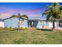 Charming home with lush lawn, palm trees, and quaint front porch under a colorful sky at 4908 Arlington Rd, Palmetto, FL 34221