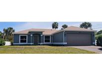 Charming one-story home with a two-car garage, palm trees, and a well-manicured lawn at 5578 Thyer St, North Port, FL 34288