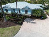 Stunning coastal home with lush landscaping, beautiful paver driveway, and a stylish light blue exterior at 5608 Holmes Blvd, Holmes Beach, FL 34217