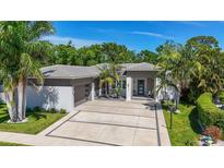 Beautiful single-story home featuring a wide driveway, modern design, and tropical landscaping at 5856 Meriwether Pl, Sarasota, FL 34232