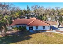 Charming single-story home with a terra cotta tile roof surrounded by lush landscaping at 670 Venice Ln, Sarasota, FL 34242
