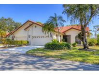 Charming single Gathering home featuring a three-car garage, landscaped yard, and a red tile roof at 7261 Villa D Este Dr, Sarasota, FL 34238