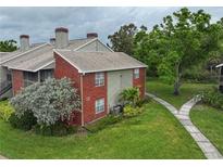 Townhome exterior with brick accents, well-maintained lawn, mature landscaping, and a walking path at 9100 Dr Martin Luther King Jr N St # 205, St Petersburg, FL 33702