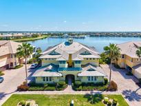 Waterfront condo building featuring a unique roofline with palm trees, landscaping, and a waterfront view at 1123 Riverscape St # D, Bradenton, FL 34208