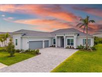 Charming single-story home featuring a tile roof, a three-car garage, and a well-manicured lawn at 12557 Galapagos Ct, Venice, FL 34293