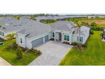 Charming single-story home with a gray tile roof, well-manicured lawn, and a gray brick driveway at 12557 Galapagos Ct, Venice, FL 34293