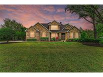Beautiful stone home featuring a manicured lawn and colorful landscaping at 22235 Panther Loop, Bradenton, FL 34202
