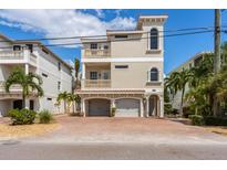 Three-story home featuring a two-car garage, balconies, a stucco exterior, and a brick-paved driveway at 2309 Avenue C # 200, Bradenton Beach, FL 34217