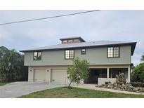 Two-story home featuring a light green exterior, multiple garage doors, and professionally landscaped yard at 33 Tee View Pl, Rotonda West, FL 33947