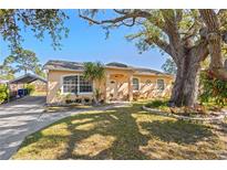 Charming single-story home featuring a well-manicured lawn and a mature shade tree at 3883 Tampico Dr, Sarasota, FL 34235