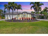 Stunning single-story home featuring a circular driveway, lush landscaping, and elegant architectural details at 435 La Sila Ct, Punta Gorda, FL 33950