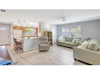Bright living room with hardwood floors, ceiling fan, and an open flow to the kitchen area at 4420 Tecumseh Trl # 38, Sarasota, FL 34233