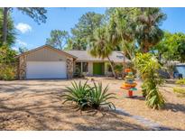 Charming single-story home featuring a well-manicured yard, stone accents and a bright green front door at 480 58Th St, Sarasota, FL 34243
