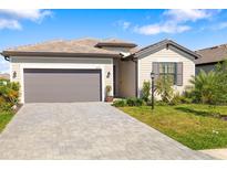 Charming single-story home with a gray paver driveway, a two-car garage, and beautiful landscaping at 5235 Coral Reef Way, Bradenton, FL 34211