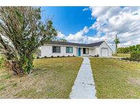 Charming single-story home boasts a manicured lawn, flower beds, and a welcoming walkway at 7002 Primm Pl, North Port, FL 34287
