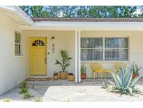 Inviting front porch features a bright yellow door, potted plants, and chairs for relaxing at 807 Harbor Ave, Ellenton, FL 34222